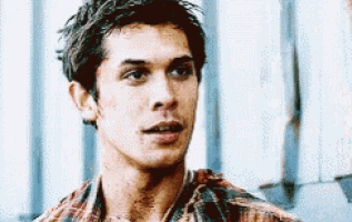 a young man in a plaid shirt is looking at the camera .
