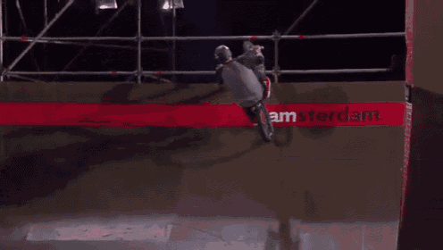 a person riding a bike on a ramp with amsterdam written on the wall behind them