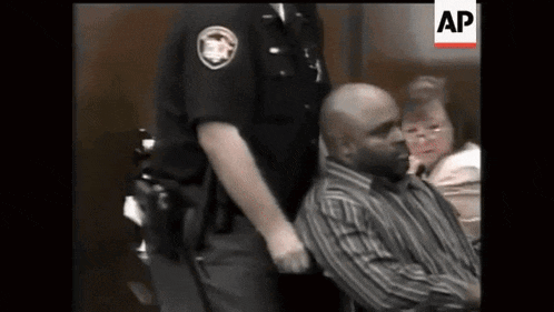 a man in a wheelchair is being held by a police officer .