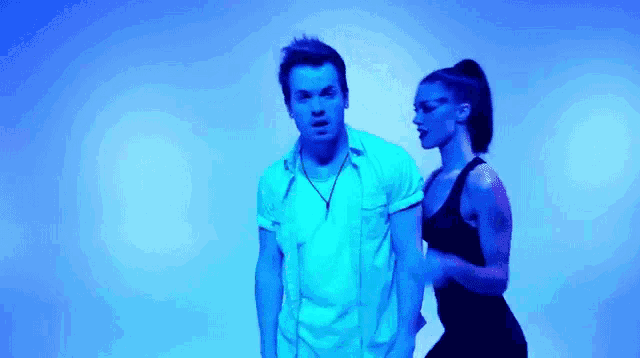 a man and a woman are dancing in front of a blue light .