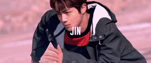 a young man wearing a black jacket and a red shirt is kneeling down .