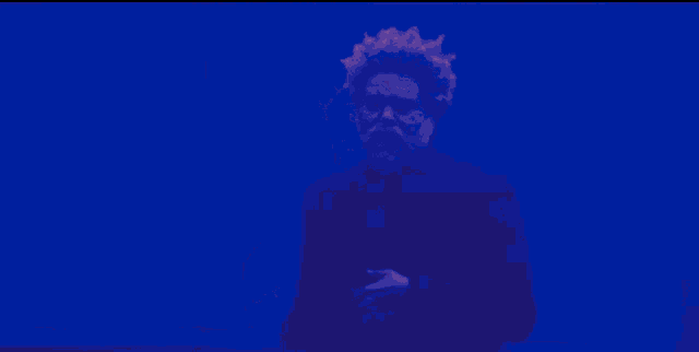 a man with a beard is standing in front of a purple wall .