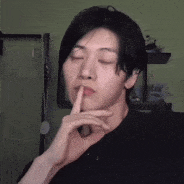 a young man with his eyes closed and his finger on his lips