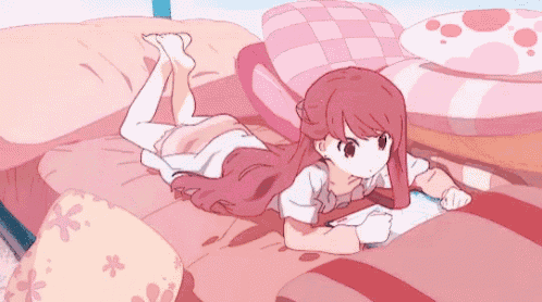 a girl is laying on her stomach on a bed with a book .