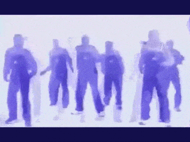 a group of people in blue overalls are dancing in a line