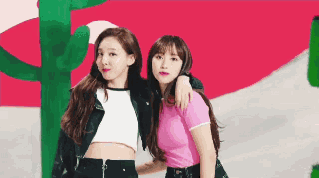 a couple of women standing next to each other with a cactus in the background