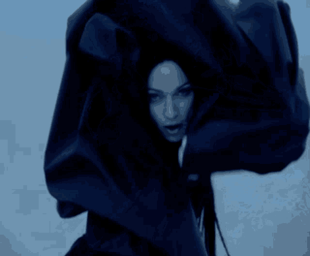 a woman in a black coat is dancing in the wind