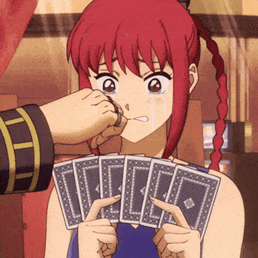 a girl with red hair is crying while holding a bunch of cards