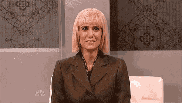 a woman in a suit is sitting in a chair and smiling .