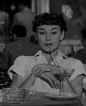 a woman is drinking a martini through a straw .