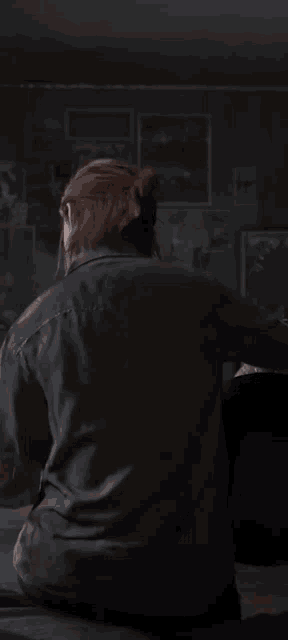 a woman in a black shirt is sitting in a dark room