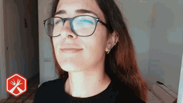 a woman wearing glasses and a nose ring smiles