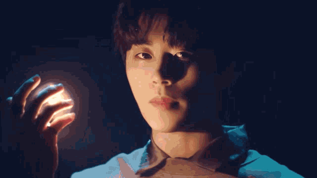 a close up of a person 's face with a light coming from their hand