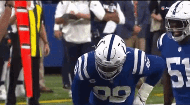 a football player with the number 99 on his jersey is kneeling down on the field