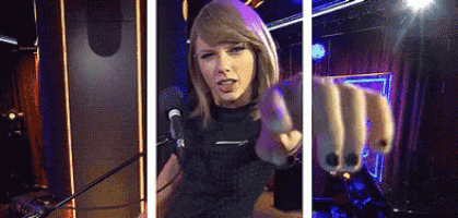 a woman is pointing at the camera while singing into a microphone .