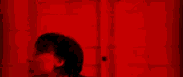 a person is standing in a dark room with red lights behind them .