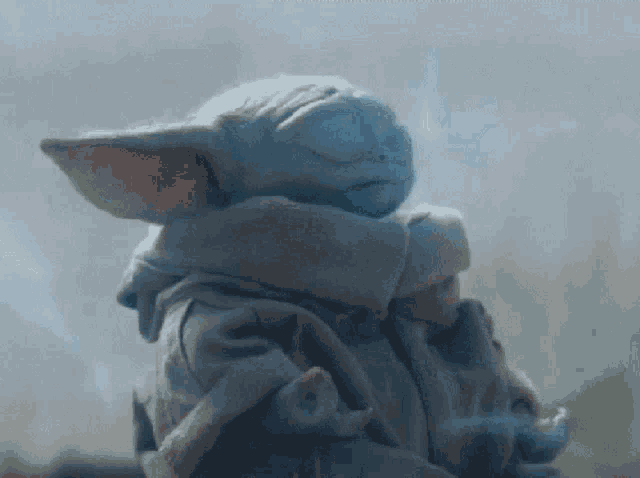 a baby yoda statue with its eyes closed and a scarf around its neck