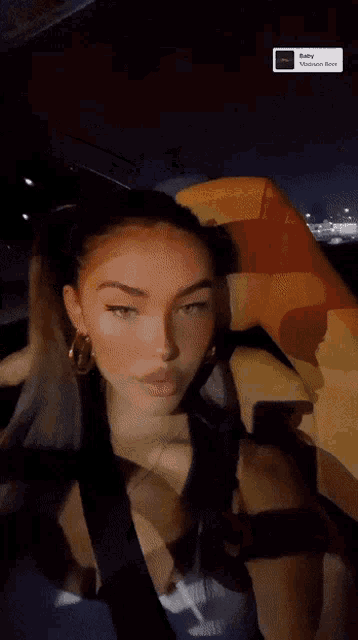 a woman is sitting in a car with a baby madison remix sticker on the bottom