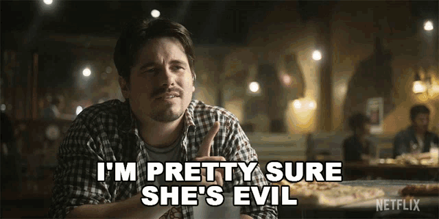 a man in a plaid shirt says i 'm pretty sure she 's evil in front of a pizza