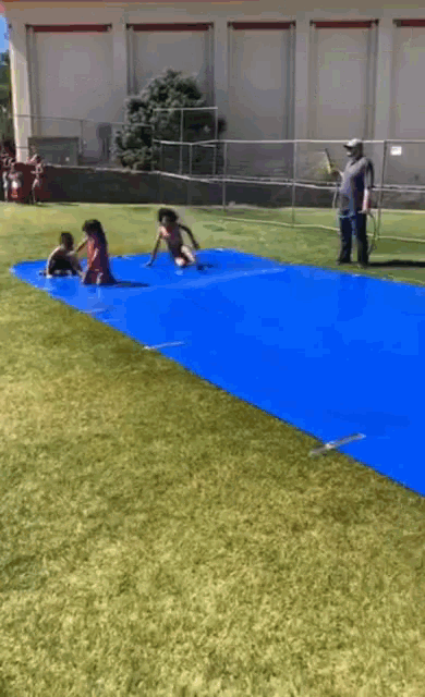 children are playing on a blue mat on a field