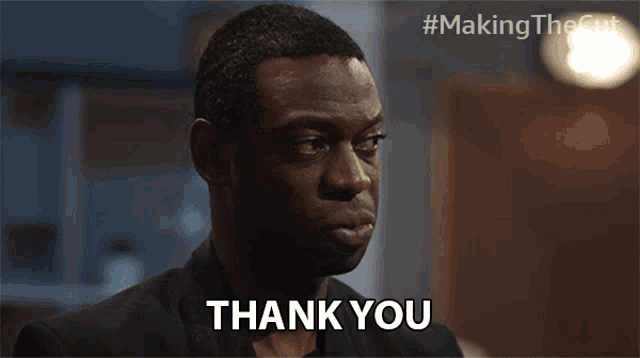 a man in a suit says thank you in front of a blurred background