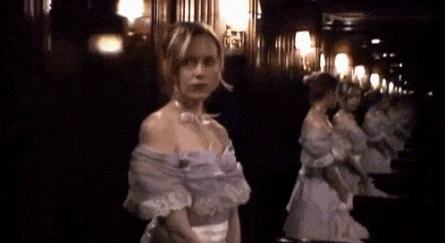 a woman in a white dress is standing in front of a mirror in a dark room .
