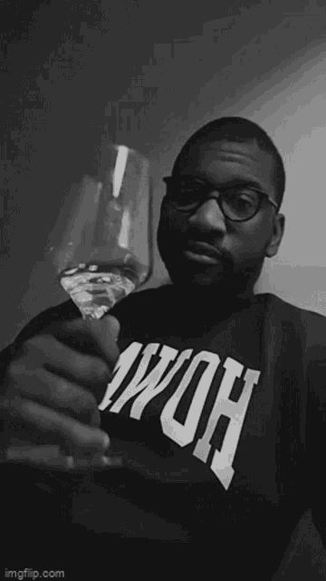 a man wearing a shirt that says wow is holding a wine glass .