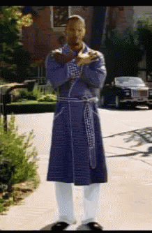 a man wearing a purple robe is standing on a sidewalk