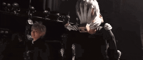 a couple of people are standing next to each other on a stage in a dark room .