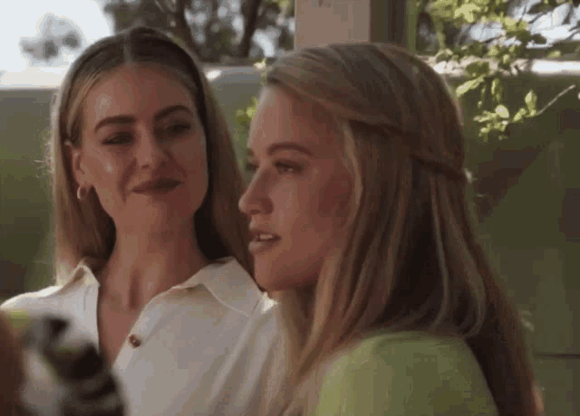 two blonde women are standing next to each other and looking at something