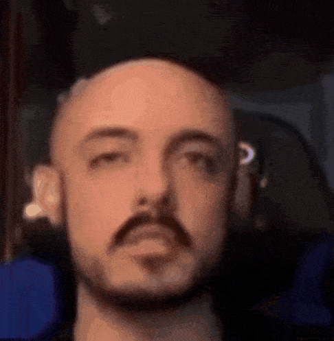 a man with a beard is wearing headphones and making a funny face .