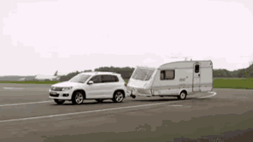 a white car is towing a caravan on a runway