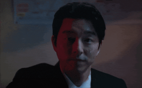 a man in a suit and tie with blood on his face looks at the camera