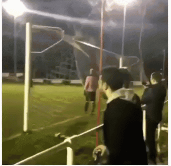 a group of people are standing on a soccer field at night .
