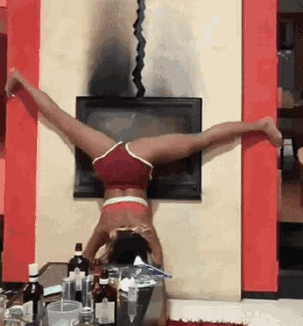 a woman is doing a handstand in front of a fireplace in a living room