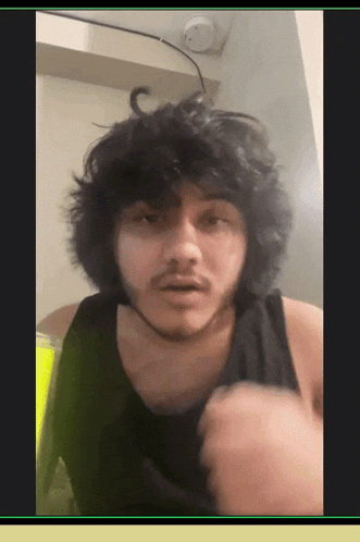 a man with curly hair and a beard is wearing a black tank top ..