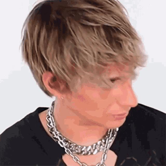 a young man wearing a silver chain around his neck
