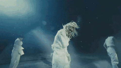 a woman in a white dress is dancing in a dark room with other people .