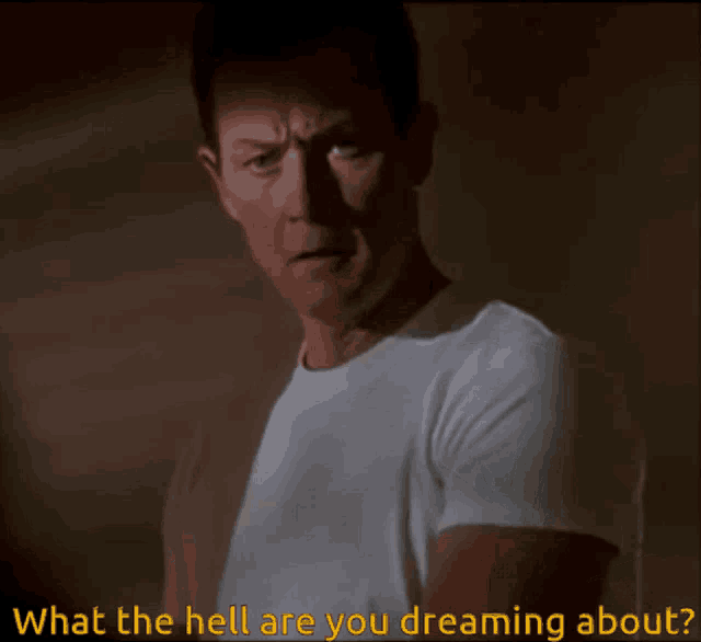 a man in a white t-shirt is asking what the hell are you dreaming about