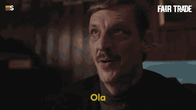 a man with a mustache is smiling and says ola in yellow