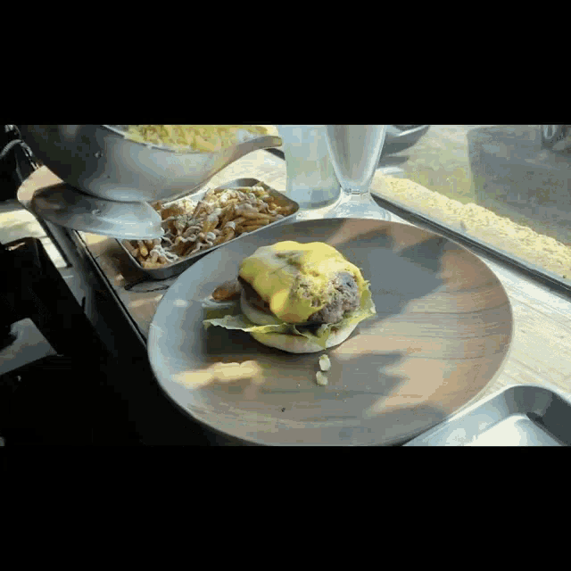 a hamburger with cheese and lettuce on a bun on a wooden plate
