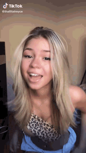 a young woman is making a funny face while wearing a leopard print top and shorts .