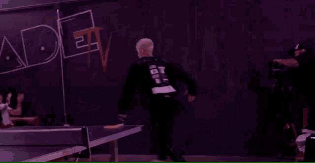 a group of people are playing ping pong in front of a fade tv sign