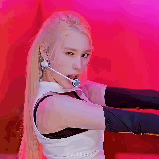 a woman with long blonde hair is wearing a white top and black gloves and has a microphone in her mouth