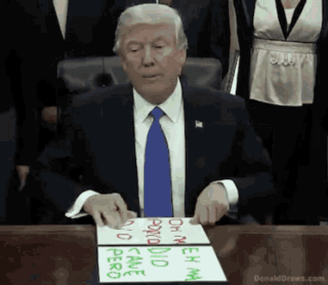 donald trump is sitting at a desk with a sign that says donalddraws.com