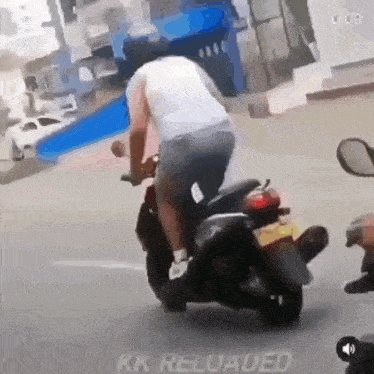 a man is riding a scooter down a street in a video that says kk reloaded