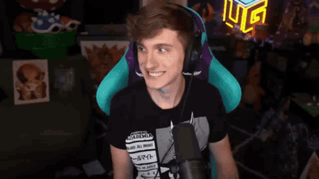 a man wearing headphones and a t-shirt that says my hero academia is smiling in front of a microphone