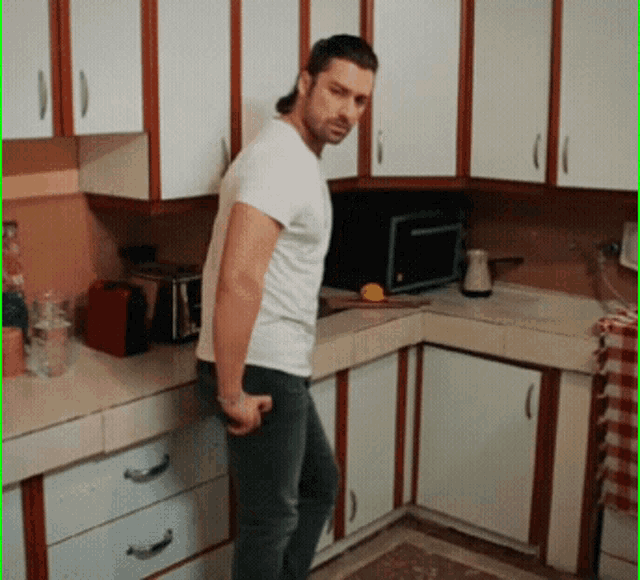 a man in a white shirt is standing in the kitchen