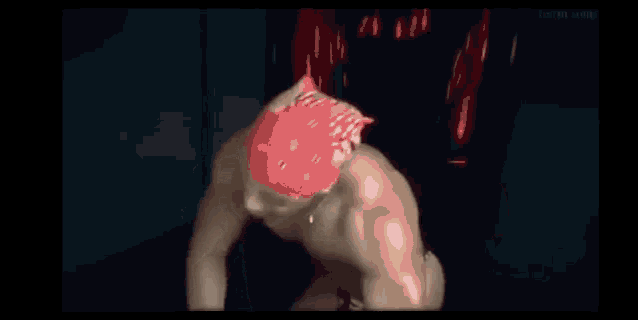 a shirtless muscular man wearing a red bandana and a necklace is giving a middle finger .
