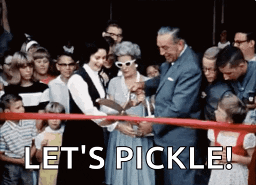 a man and woman are cutting a red ribbon with the words let 's pickle behind them .
